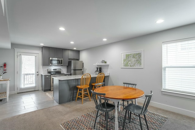 dining area with recessed lighting, light colored carpet, and baseboards