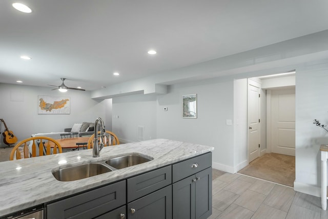 kitchen with recessed lighting, gray cabinetry, a sink, a ceiling fan, and light stone countertops