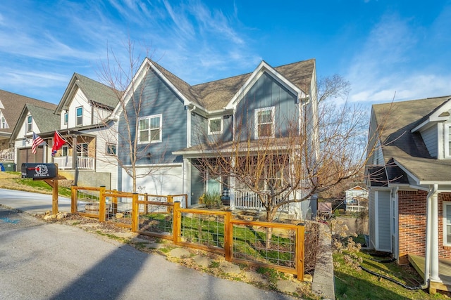 view of front of property featuring a fenced front yard, a garage, driveway, a gate, and board and batten siding