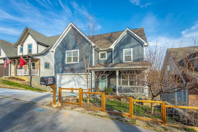 view of front of home featuring a fenced front yard, roof with shingles, a porch, board and batten siding, and a garage