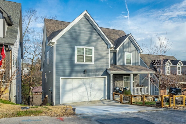 traditional-style house with a garage, a shingled roof, concrete driveway, covered porch, and board and batten siding