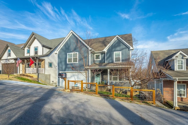 view of front of house with a garage, covered porch, a fenced front yard, and board and batten siding