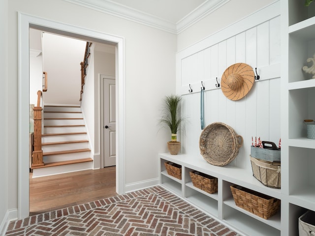 mudroom with brick floor, baseboards, and ornamental molding