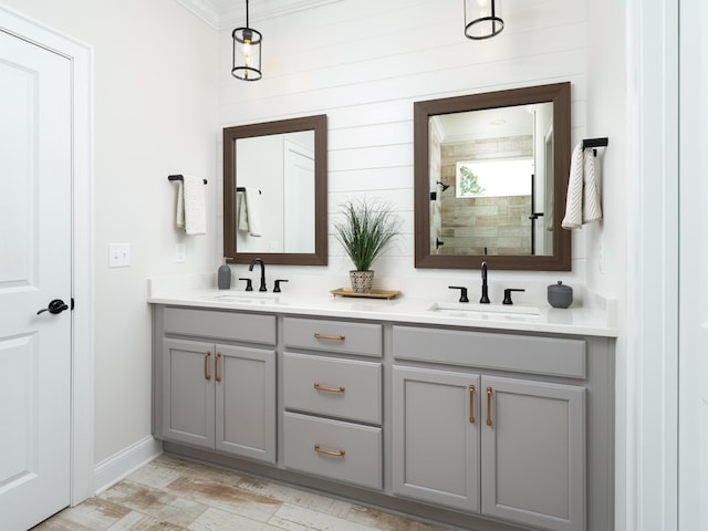 bathroom featuring double vanity, baseboards, a sink, and tiled shower