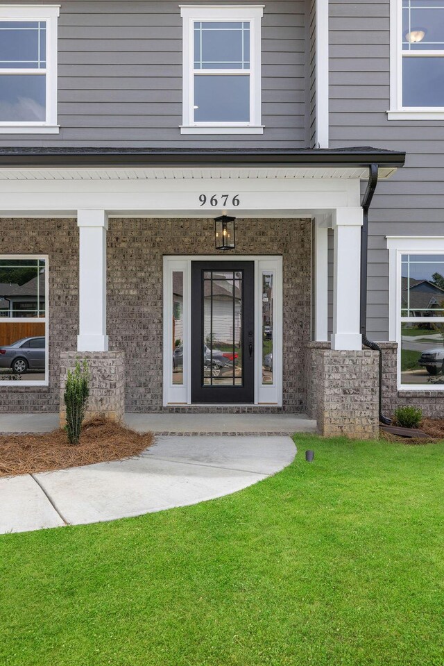 9676 Mayfly Rd # 10, Ooltewah, TN 37363 - view of exterior entry featuring brick siding, a lawn, and covered porch