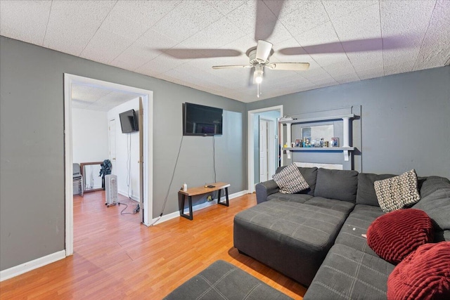 living area with light wood finished floors, baseboards, and ceiling fan