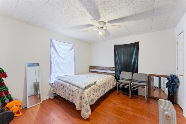 bedroom featuring radiator, a ceiling fan, and wood finished floors