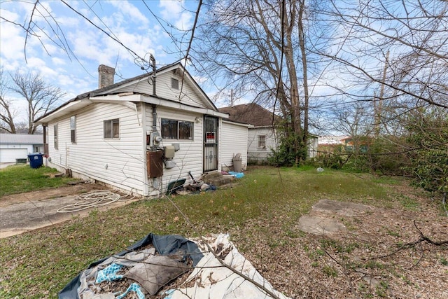 view of side of home featuring a lawn and a chimney