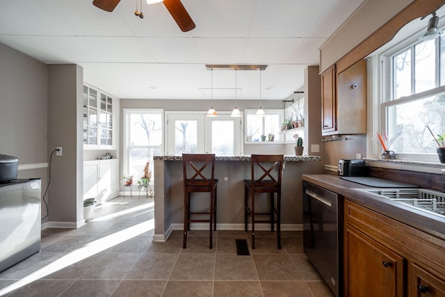 kitchen with plenty of natural light, brown cabinets, dishwasher, and a peninsula