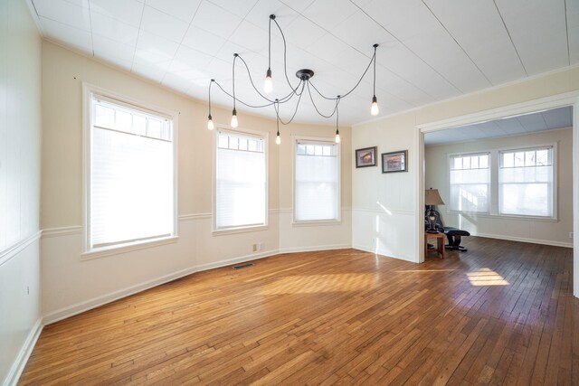 unfurnished dining area featuring crown molding, baseboards, and hardwood / wood-style flooring