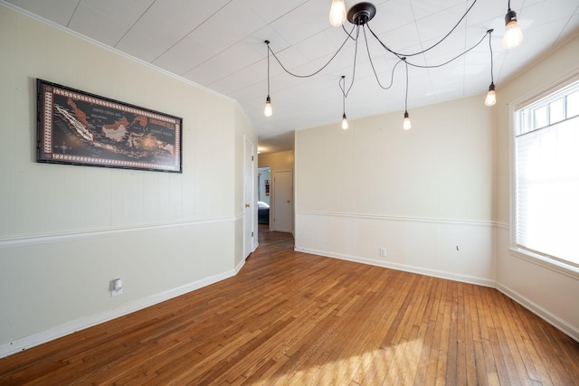 unfurnished room with hardwood / wood-style flooring, crown molding, and a wealth of natural light