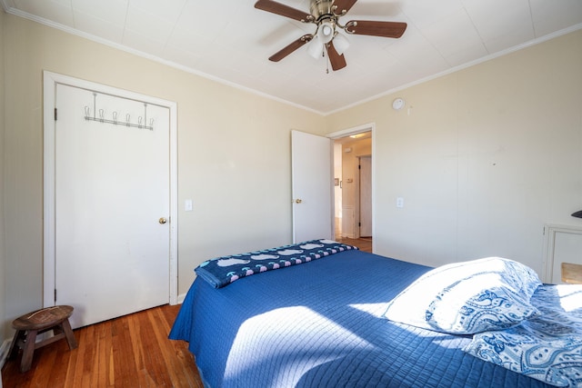 bedroom with ceiling fan, ornamental molding, and wood finished floors