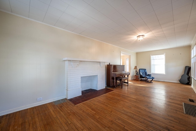 unfurnished living room featuring wood-type flooring, a fireplace, visible vents, and ornamental molding