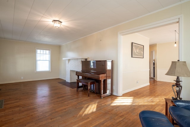 living room featuring hardwood / wood-style flooring, a fireplace, visible vents, baseboards, and ornamental molding