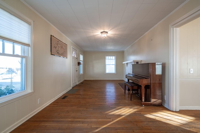 interior space featuring baseboards, wood-type flooring, visible vents, and crown molding