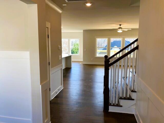 hallway with dark wood-style flooring, visible vents, and baseboards