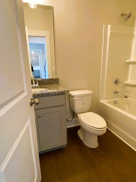 full bath with shower / washtub combination, vanity, toilet, and wood finished floors