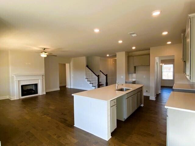 kitchen featuring light countertops, a fireplace, dark wood finished floors, and a kitchen island with sink