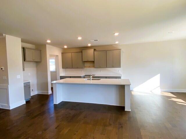 kitchen with a kitchen island with sink, recessed lighting, baseboards, gray cabinets, and dark wood finished floors