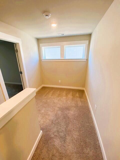 empty room with carpet floors, visible vents, and baseboards