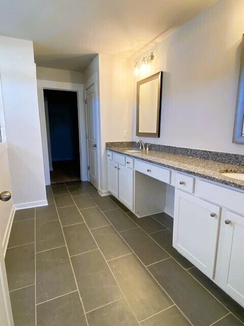 bathroom featuring tile patterned flooring, a sink, baseboards, and double vanity