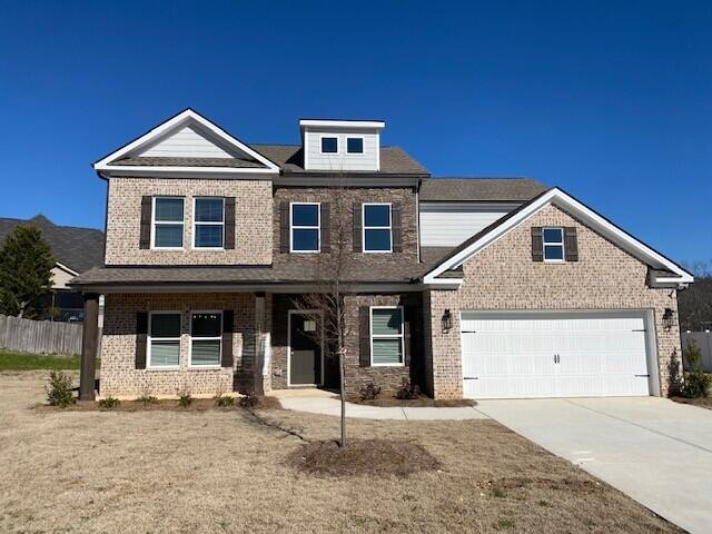 craftsman-style home featuring driveway, brick siding, and fence