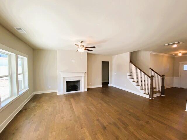 unfurnished living room featuring visible vents, a fireplace, stairway, and wood finished floors