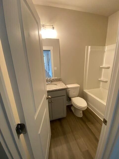 bathroom featuring toilet, shower / bathing tub combination, wood finished floors, and vanity