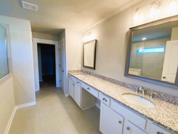 bathroom with double vanity, a sink, visible vents, and baseboards