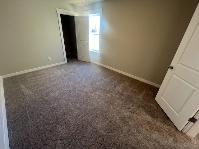 unfurnished bedroom with baseboards, visible vents, and dark carpet