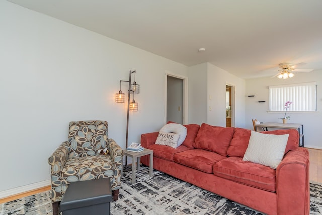 living area with wood finished floors, a ceiling fan, and baseboards