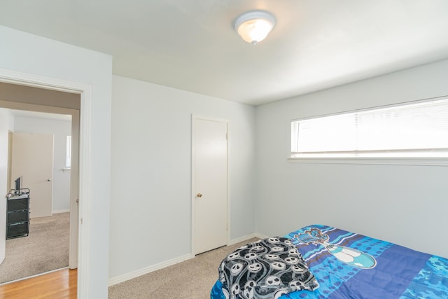 bedroom featuring light carpet and baseboards