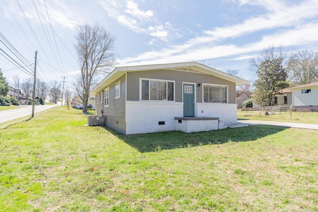 exterior space featuring crawl space, brick siding, fence, and a front lawn