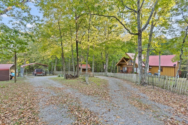 view of front facade with a fenced front yard, a detached carport, and gravel driveway