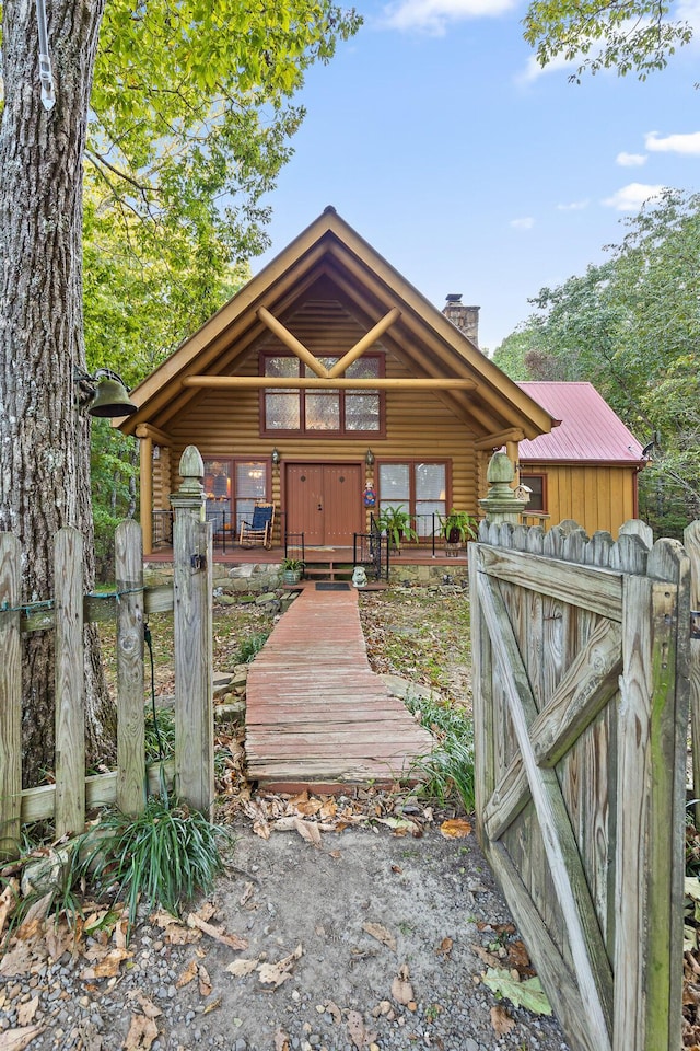 rustic home with a chimney, a gate, and log exterior