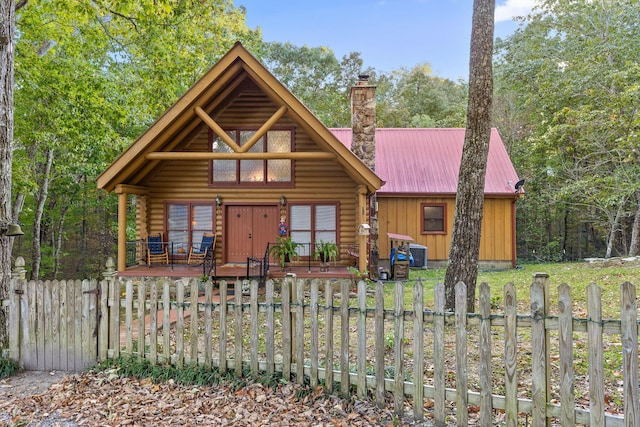 view of front of property featuring a fenced front yard, a chimney, board and batten siding, metal roof, and log siding