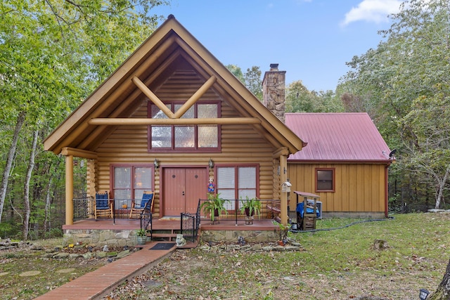 log home with a chimney, metal roof, log exterior, and a front lawn