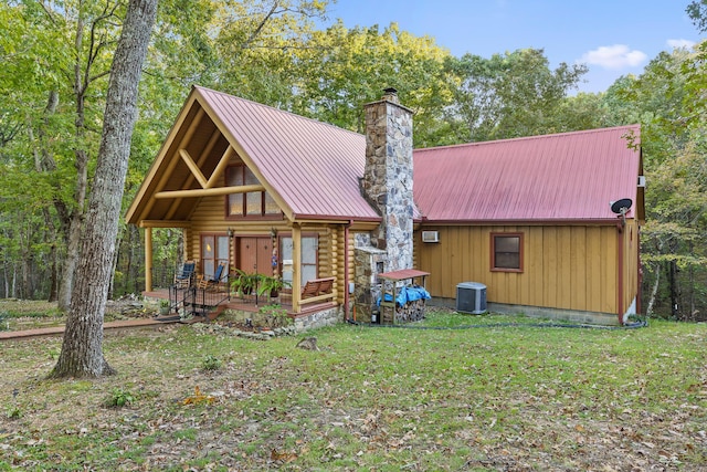 view of front facade featuring a chimney, central air condition unit, metal roof, log siding, and a front lawn