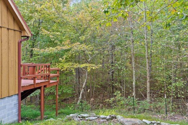 view of yard with a deck and a view of trees