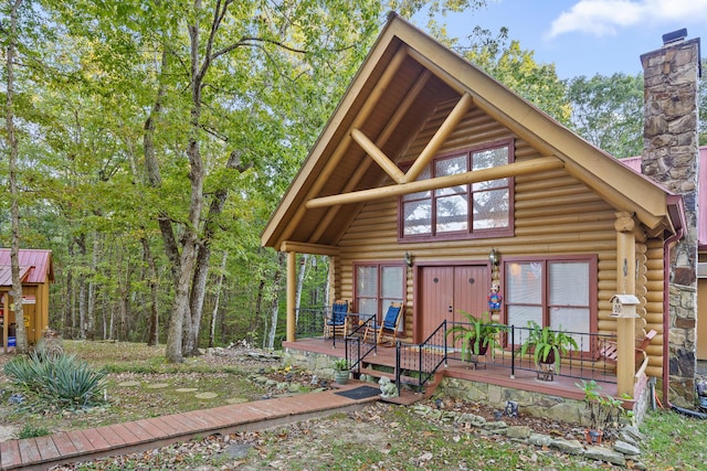 log-style house with a chimney, a wooden deck, and log siding