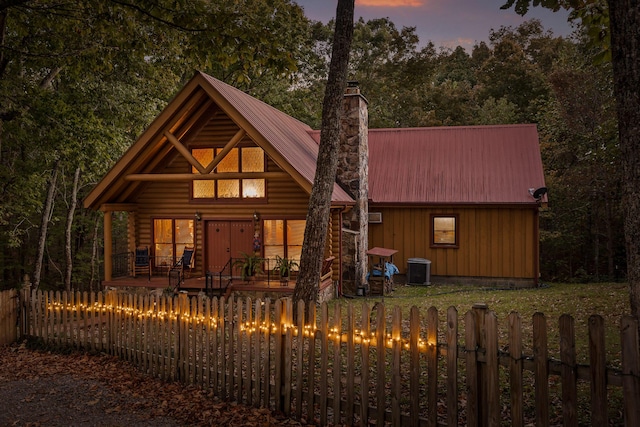 view of front of house featuring a fenced front yard, a chimney, metal roof, and cooling unit