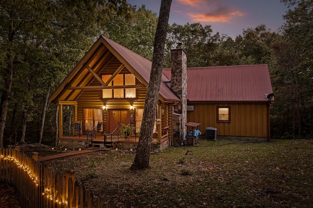 back of house with cooling unit, metal roof, a chimney, and fence