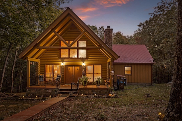 view of front of home featuring covered porch, metal roof, board and batten siding, and a chimney