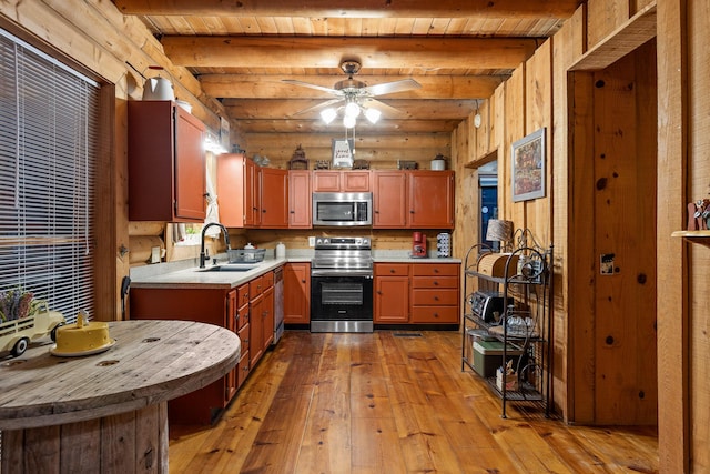 kitchen featuring rustic walls, stainless steel appliances, light countertops, light wood-type flooring, and a sink