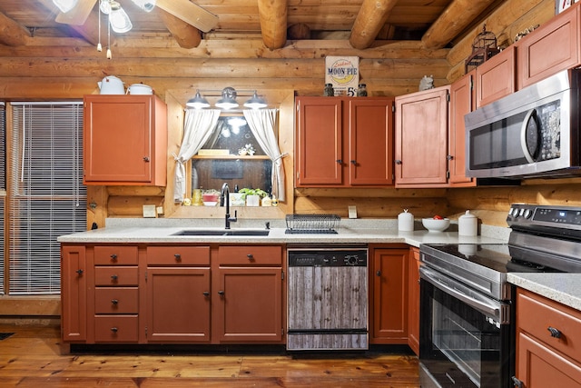 kitchen with hardwood / wood-style flooring, stainless steel appliances, a sink, log walls, and beamed ceiling