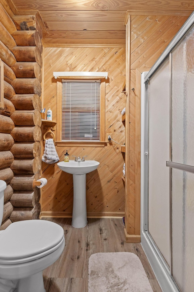 bathroom with a stall shower, baseboards, toilet, and wood finished floors