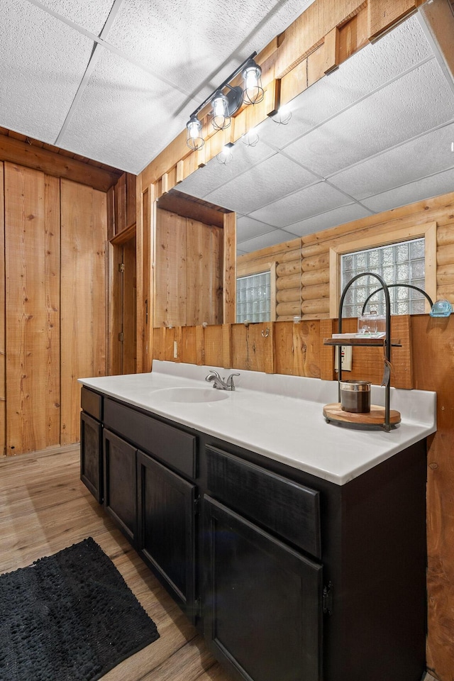 bathroom with a paneled ceiling, wood walls, and wood finished floors