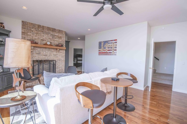 living area with recessed lighting, a fireplace, wood finished floors, baseboards, and stairs