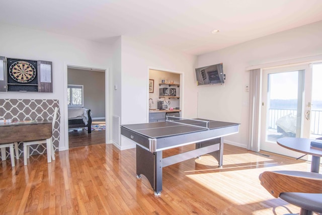 rec room with baseboards, light wood-style floors, and a healthy amount of sunlight