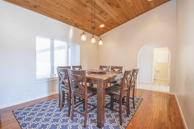 dining space with arched walkways, hardwood / wood-style floors, wooden ceiling, and baseboards